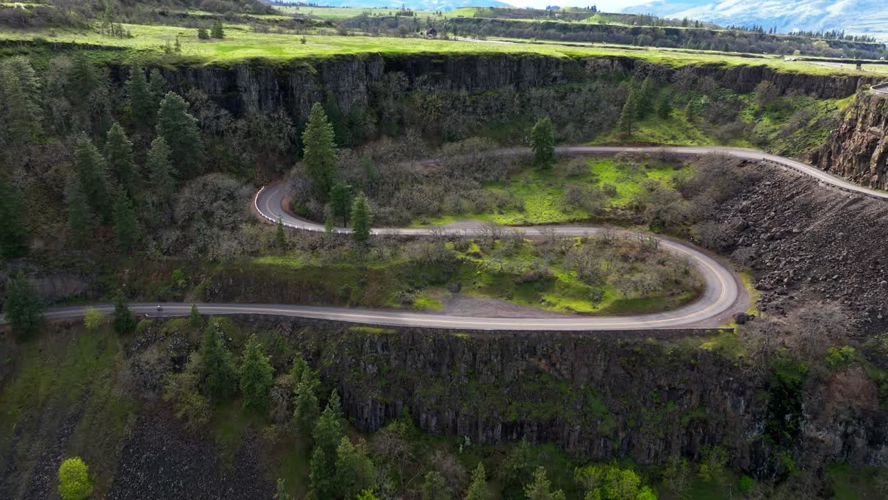 En luftoptagelse med en DJI-drone, der dolly-zoomer ind på et par hårnålesving på en vej, der fører til Rowena Crest Viewpoint i Mosier, Oregon, i Columbia River Gorge National Scenic Area.