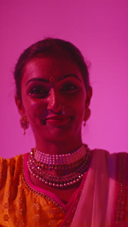 vertical video close up on face of female kathak dancer performing dance wearing traditional indian dress against purple background 2