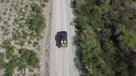 Drone-Siguiendo-Un-Coche-Conduciendo-Por-El-Camino-De-Tierra-Desde-La-Parte-Superior