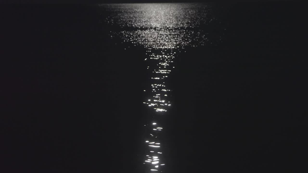 Still shot of a calm sea lit by a moonlight