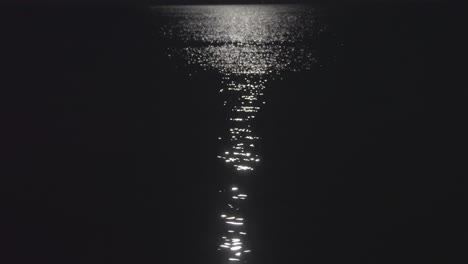 still shot of a calm sea lit by a moonlight