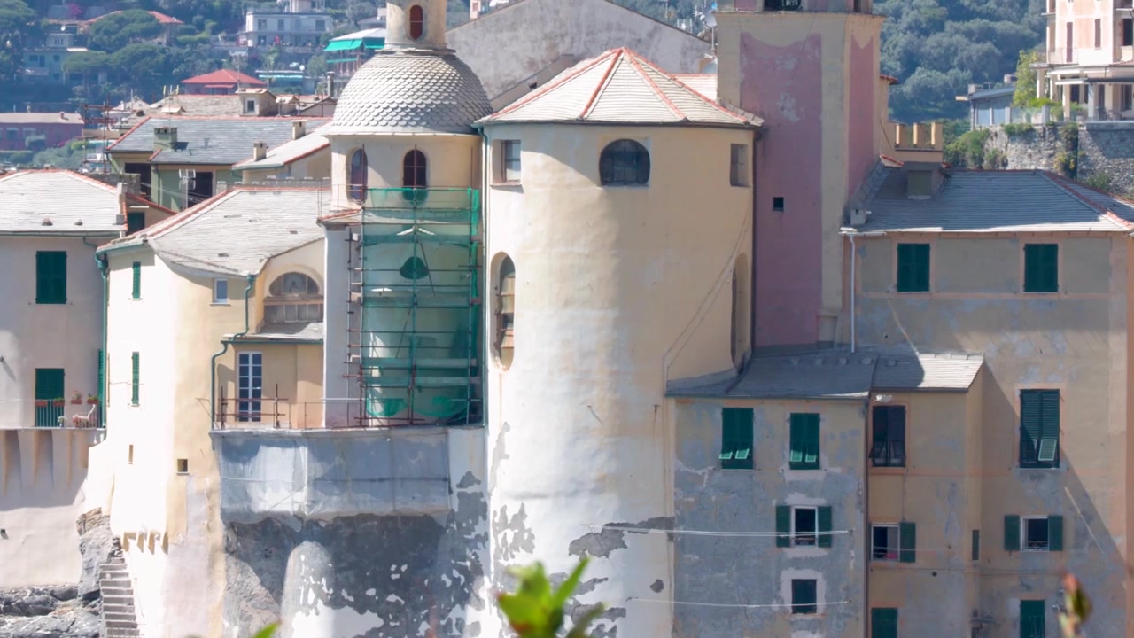 Ripresa panoramica lenta di una chiesa storica e un campanile lungo la costa della Riviera italiana.