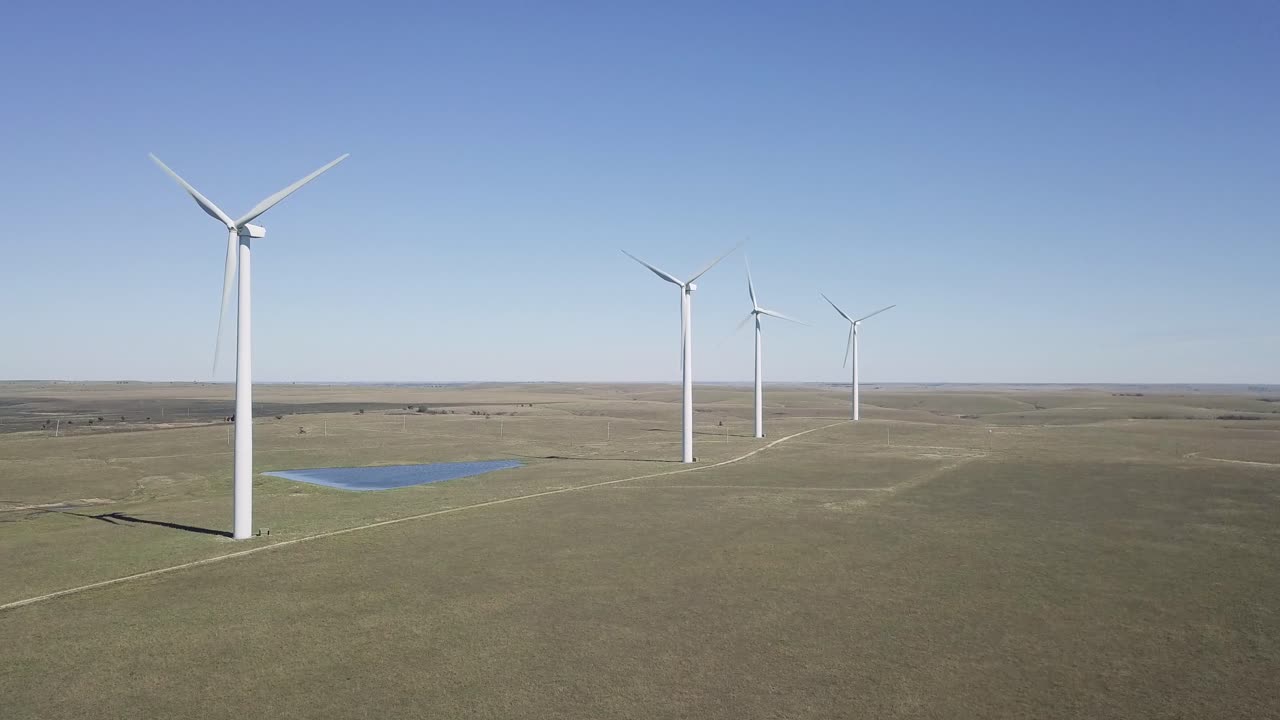 Aerial drone footage of windmills during summer over farm fields in Kansas, United States