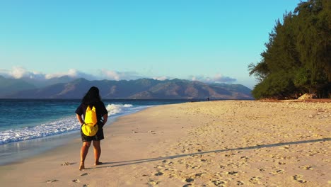 isla de ko samui, tailandia - mujer turista caminando por la playa con árboles gloriosos y cielo azul nublado arriba - primer plano