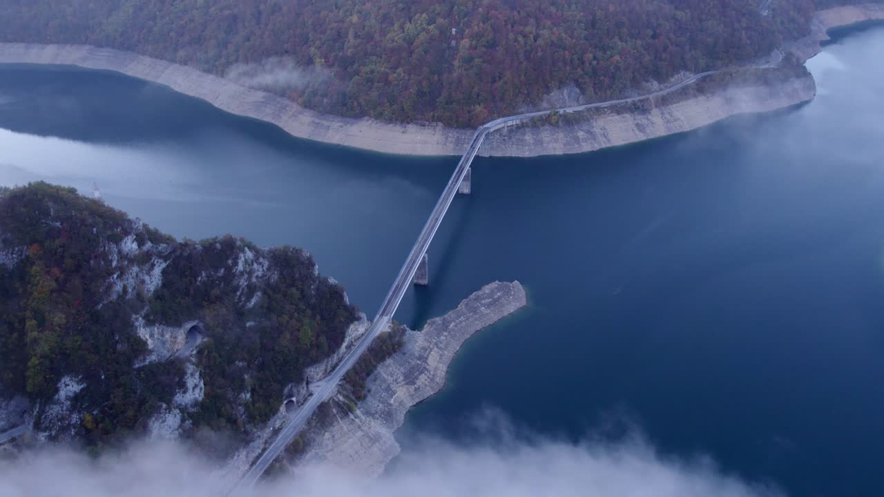 Veduta aerea di un imponente ponte sul canyon del lago Piva durante l'alba a Plužine, Montenegro, con una splendida illuminazione dell'alba, atmosfera calma, filmato drone di alta qualità che cattura momenti sereni.
