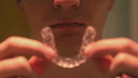 disparo en primer plano de un joven quitando sus retenedores invisalign transparentes en el baño