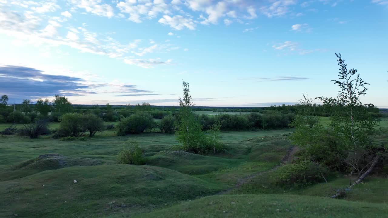 Una vista panoramica di dolci colline verdi con un cielo azzurro limpido e nuvole bianche e soffici sullo sfondo.