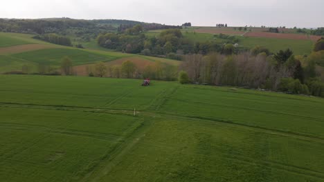 downward looking drone footage of large green meadows where a tractor is driving