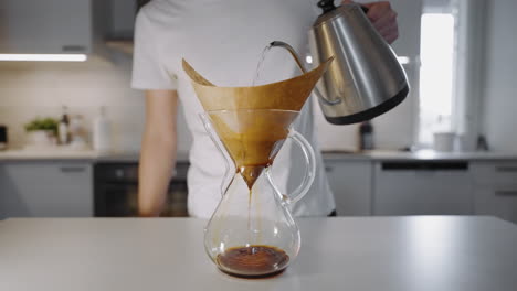 fresh drip coffee brewing, enthusiast pours water onto ground coffee in paper filter, selective focus