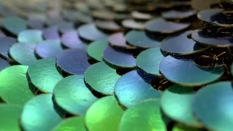 macro view of an array of blue, teal, and green sequins that are flat and reflective