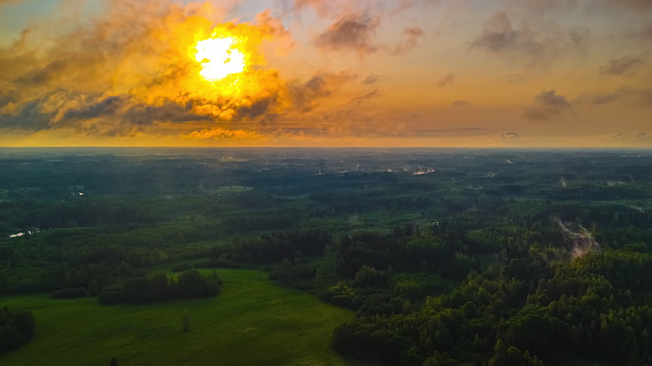 Aerial view of sunset over green forest, peaceful and serene landscape, timelapse