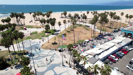 antigua bandera de gloria sobrevolando el paseo marítimo y el parque de patinaje en venice beach, los angeles california - vista aérea de paralaje en órbita