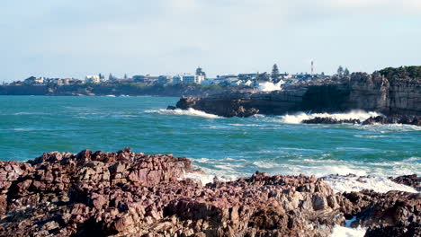 Wave smash into jagged rocks spraying white plume of water into air, slomo