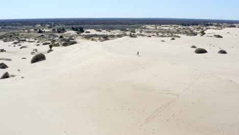 Niña-Explorando-Enormes-Dunas-De-Arena-En-Un-Desierto-Australiano-En-Un-Día-Caluroso-Y-Soleado,-Toma-Aérea-2