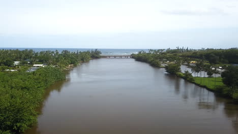 Aerial-view-along-river-approaching-estuary-and-sea,-Kauai,-Hawaii