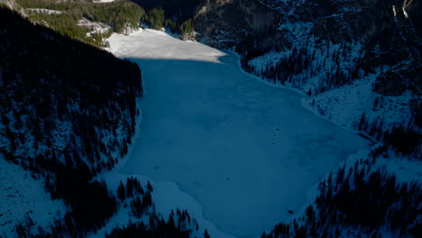 Filmische-Luftaufnahme-Des-Schattigen,-Zugefrorenen-Pragser-Wildsees