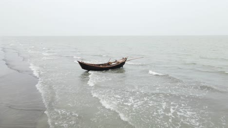 empty wooden fishing boat on kuakata sea beach with waves gently breaking underneath