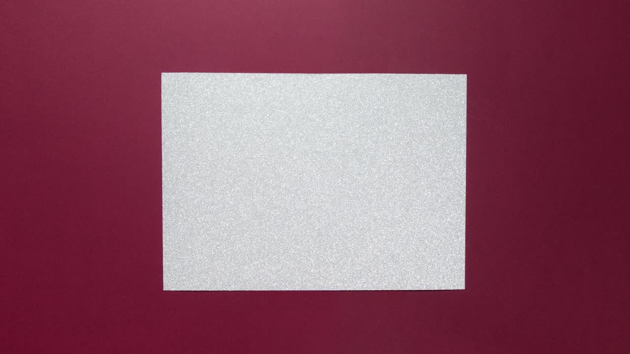 Festive silver glitter note taped with gold on a burgundy background for copy space