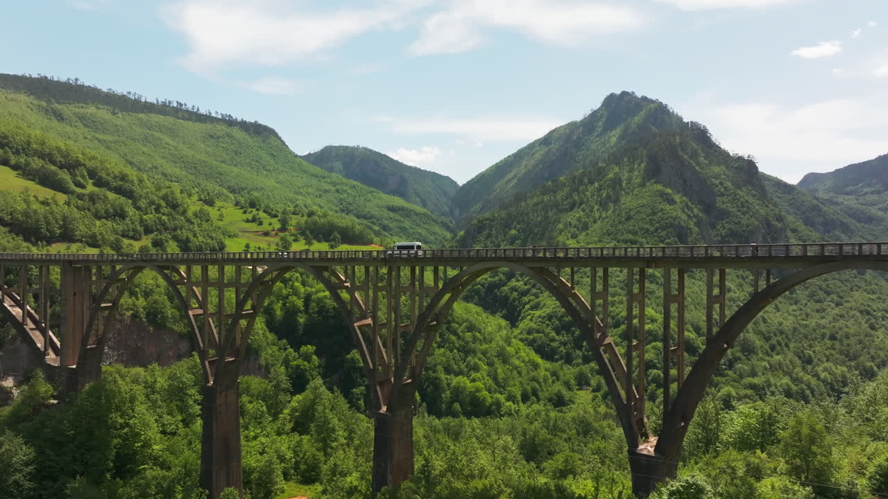 Traffic pass canyon on Tara UNESCO Montenegro bridge in lush wilderness; drone