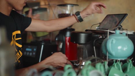 a male kitchen crew cleaning and sterilizing the coffee filter using hot water from the coffee maker in el nido, philippines - closeup shot
