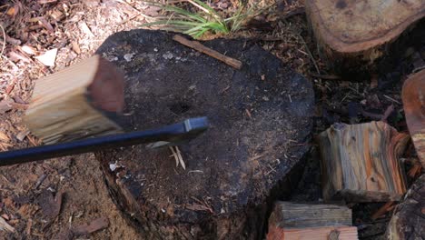 looking down at log as man splits it with axe - winter fuel - close up of axe, log, man at work, legs, work boots and work gloves - slow motion 4k