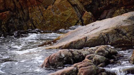 fast water hits bedrock on shoreline, slow motion medium shot