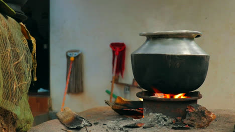 a aluminium pot is placed on a traditional fireplace with burned woods