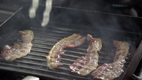 slices of bacon fried on grill