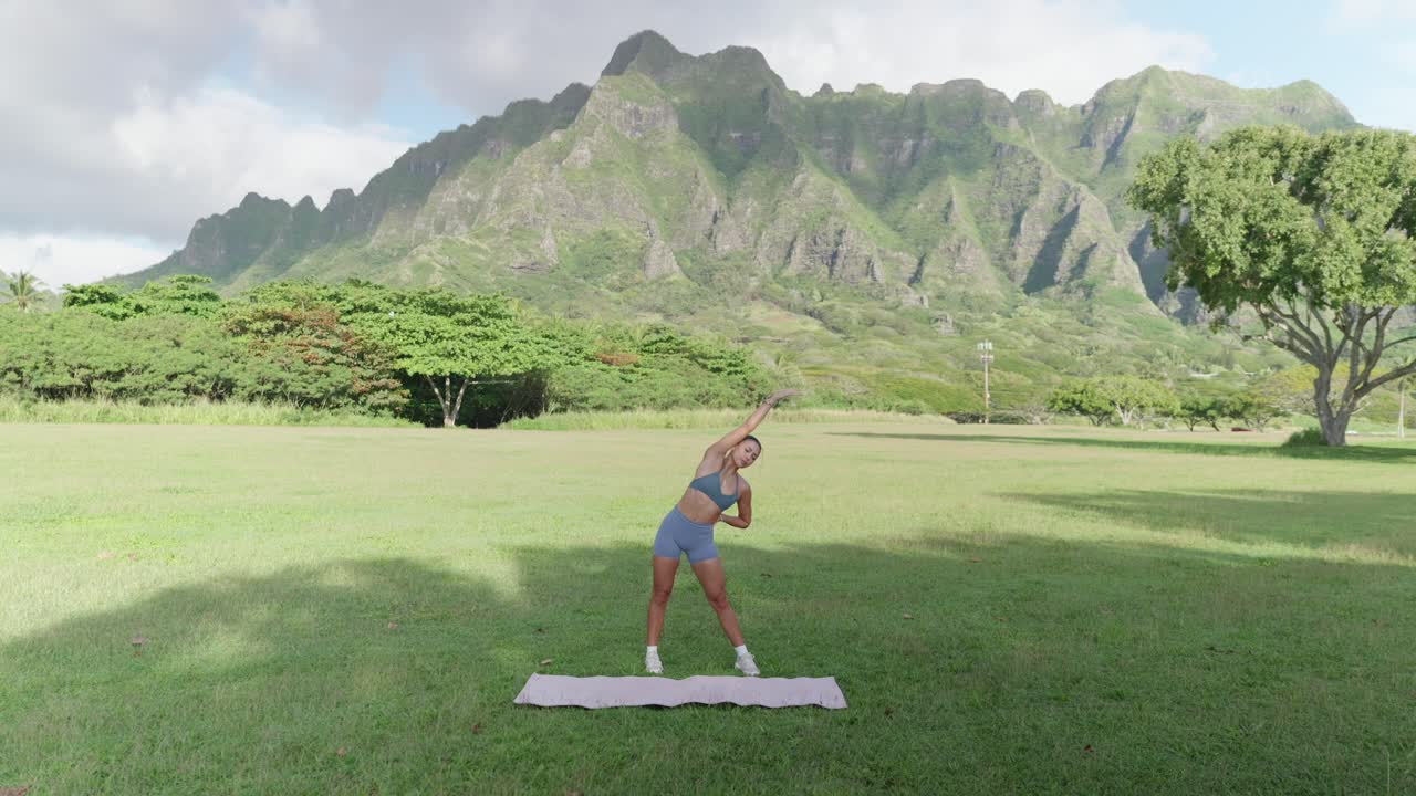 Fitness model side stretching in front of mountain