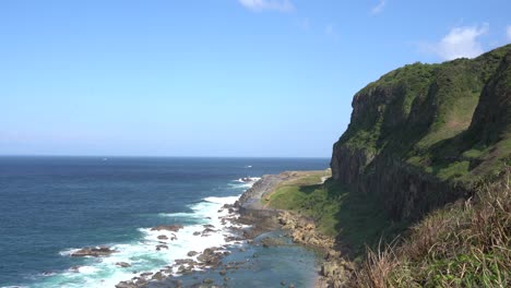 beautiful blue ocean waves crashing the rocky shore with cliffs on the side with trails