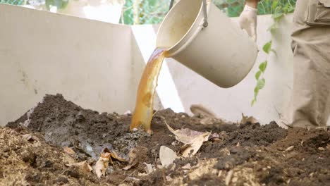 pouring water fertilizer into pile of soil