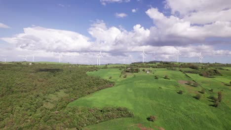 aerial background of windmill at horizon on green hill with fluffy clouds, renewable energy