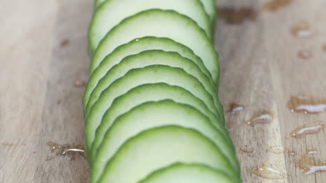 primer plano de una fila de rodajas frescas y maduras de pepino inglés en una tabla para cortar madera