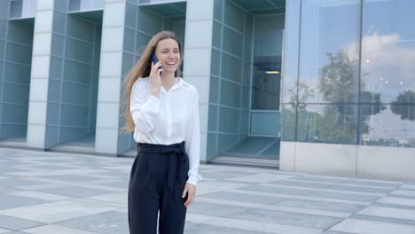 Attractive-professional-business-woman-talking-on-her-phone-outside-office