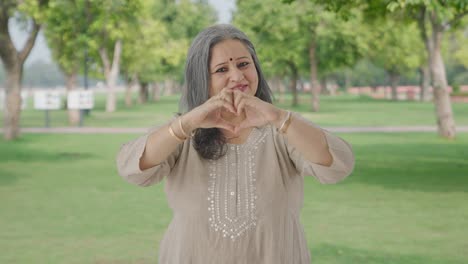 Happy-Indian-old-woman-showing-heart-sign-in-park