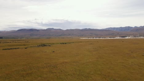 Truck-on-distant-dirt-road-swirling-up-dust-while-travelling-fast-through-dry-alpine-meadows