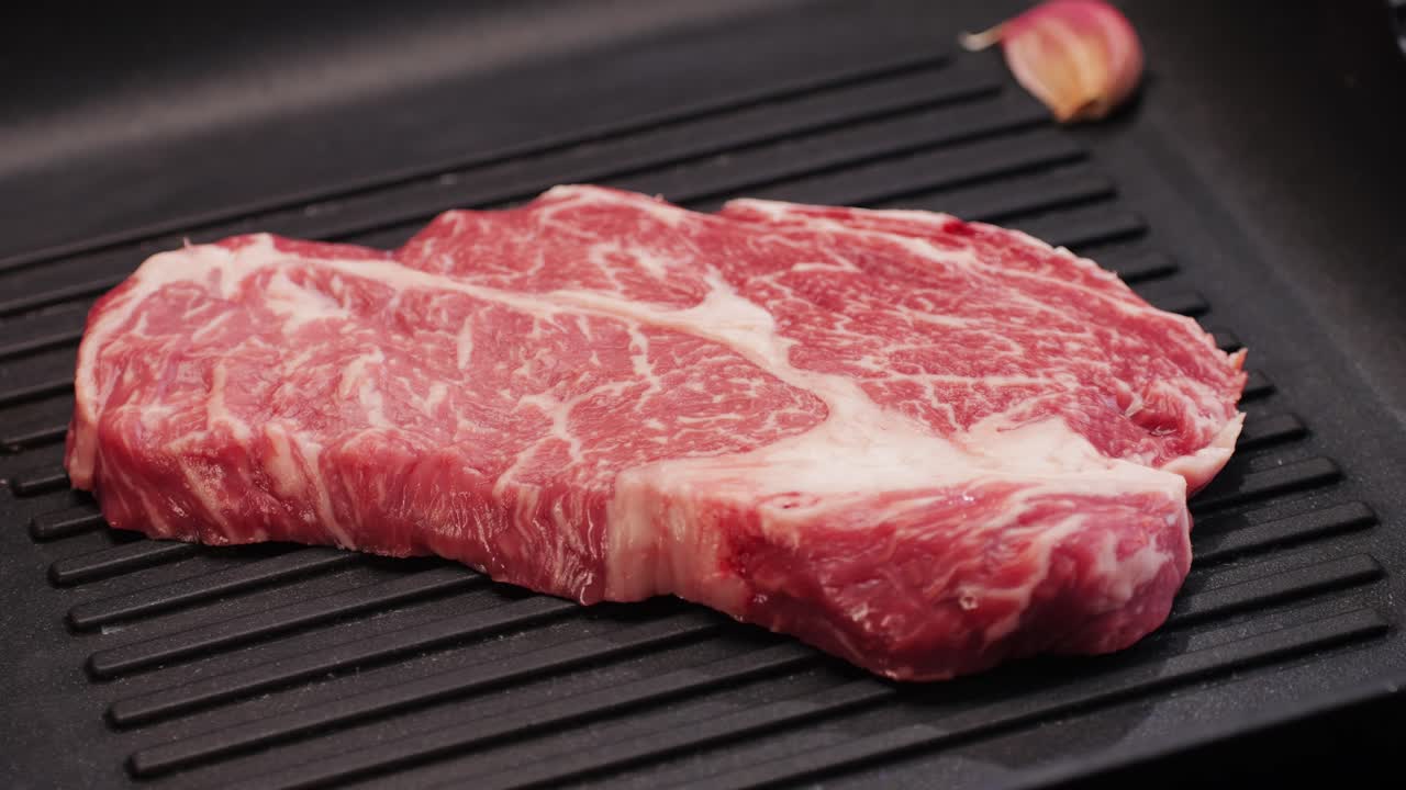 Fresh marbled beef with pepper, salt and rosemary close-up macro. Preparation to cook juicy steak on grill. Premium organic raw wagyu meat. High quality 4k footage