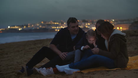 Familia-Viendo-El-Teléfono-En-La-Orilla-Del-Océano