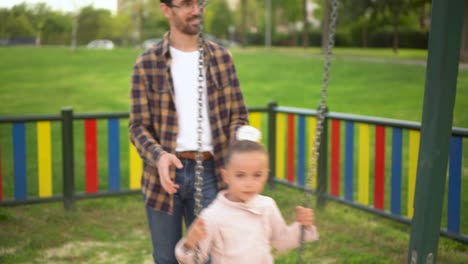 father and daughter enjoying a swing ride at the playground