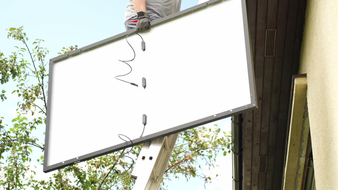 trabajador subiendo escaleras y sosteniendo un enorme panel solar, vista de la mano
