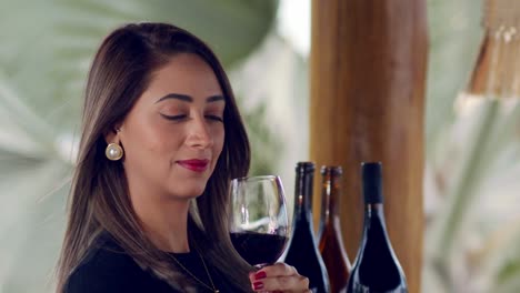 lady with a glass of red wine with three bottles in the background on a wine tasting - close up slow motion