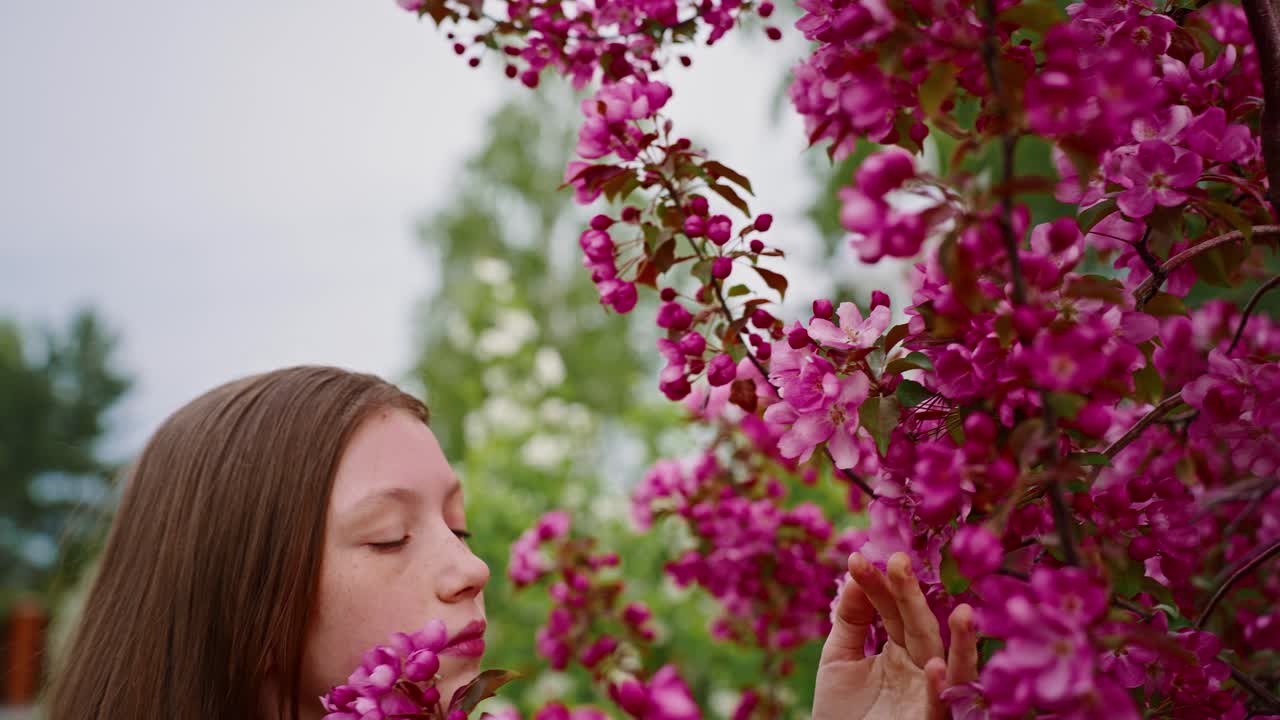 Girl smelling pink flowers in a garden