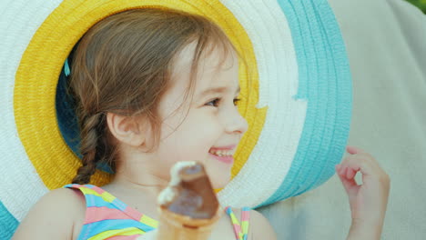 una chica alegre con sombrero come helado relajante en el resort con niños 4k video