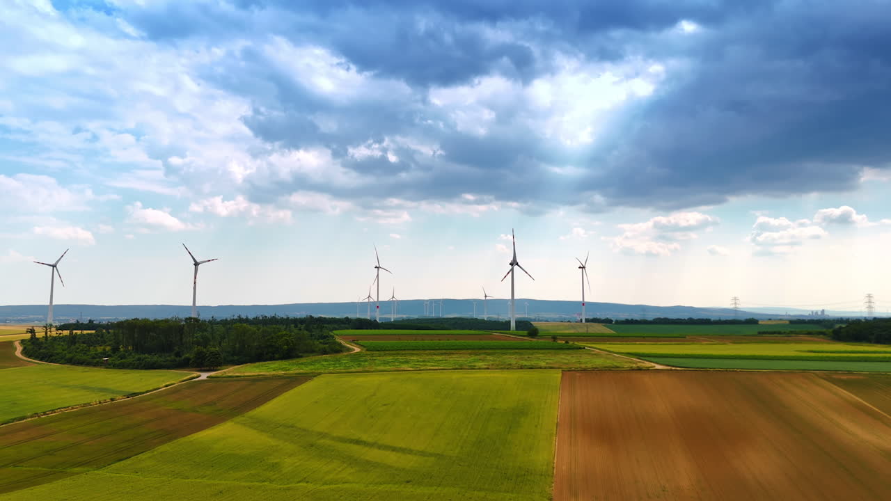 Wind turbines stand tall in green fields. Wind turbines dot green fields under clouds, highlighting renewable energy in a rural setting