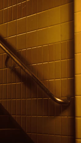 a close-up shot of a handrail on a staircase with yellow tiles