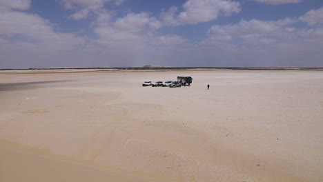 Cars-walking-on-the-sand-under-a-cloudy-sky-in-the-desert---wide-shot