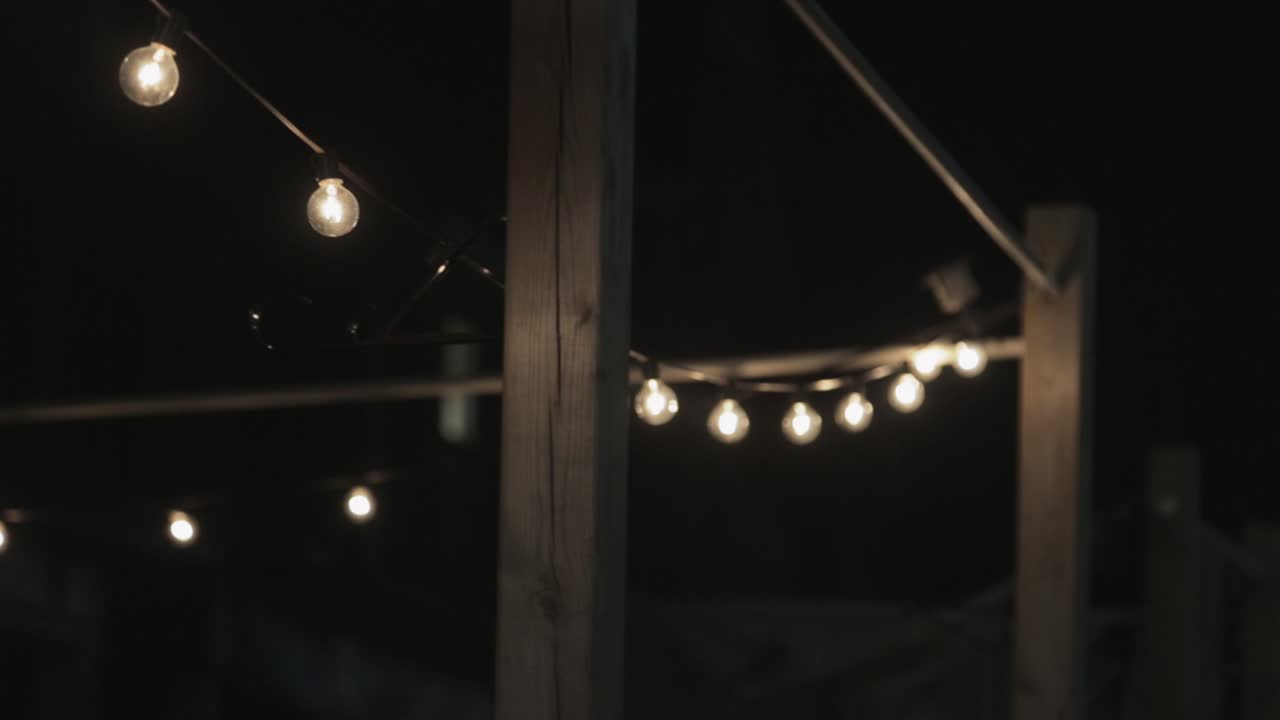 Bulbs Hanging Outside Glowing With White Bright Light - Pan Up Shot