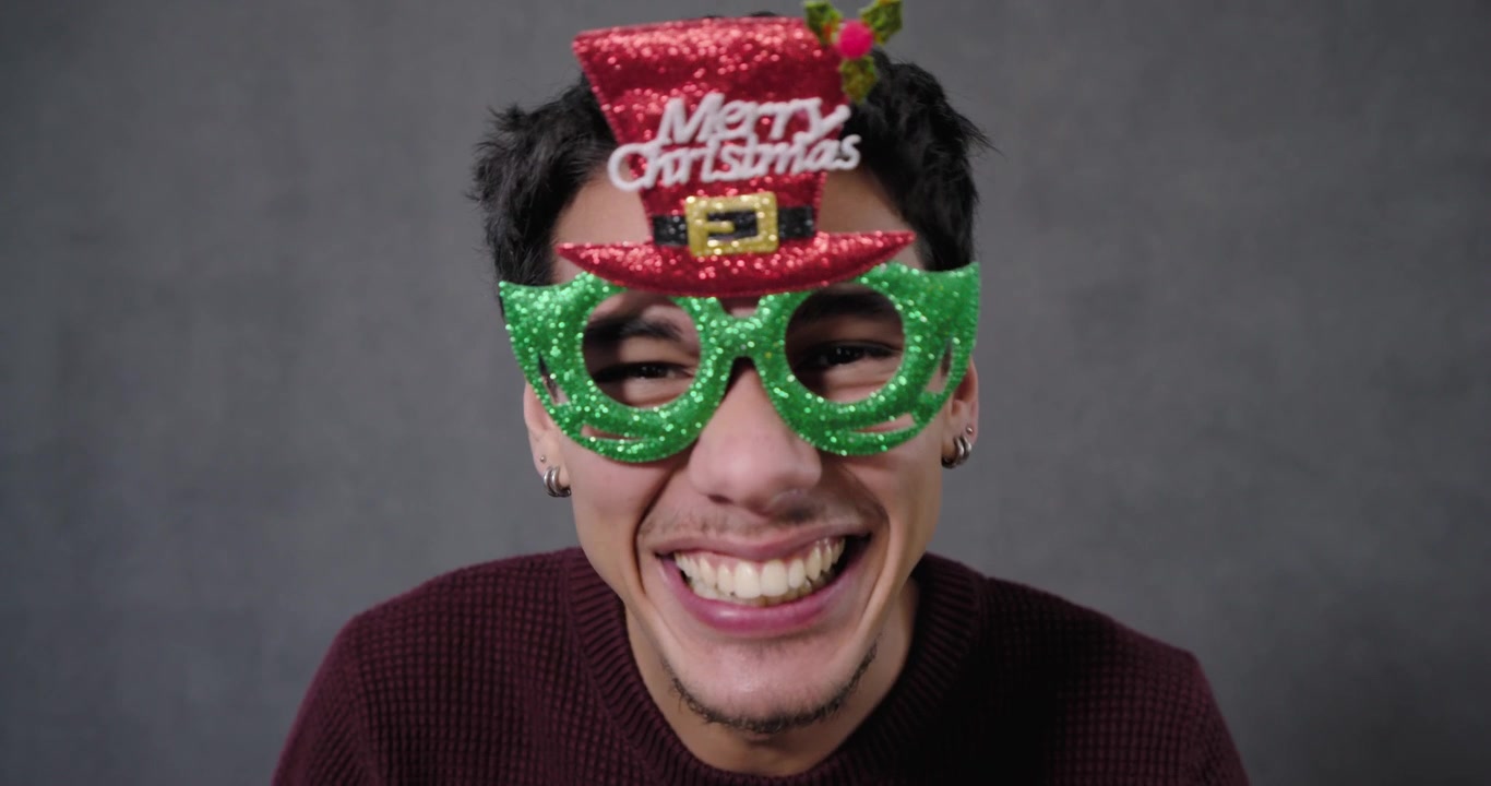 African American man smiling then reaching, placing green Xmas glasses in studio, adjusting to demo
