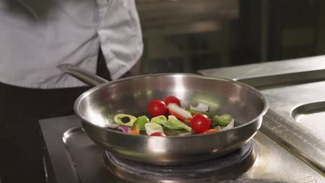 chef cocinando verduras en una sartén