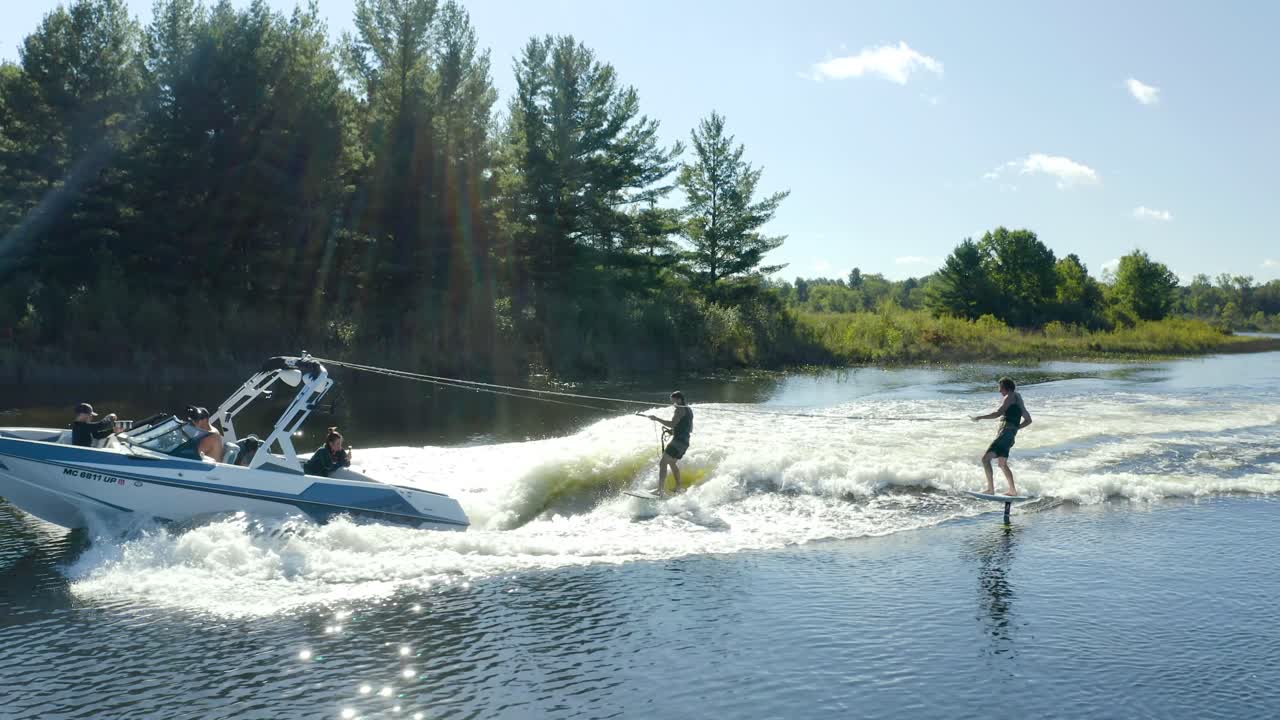 2 wake surfers behind a boat on a lake in Michigan